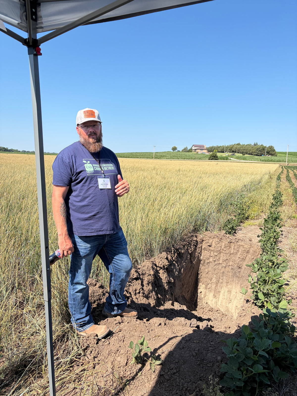 Josh McClain standing in a Kernza field beside a soil pit